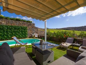 a patio with a table and chairs and a swimming pool at Vista Golf 20 by VillaGranCanaria in Maspalomas +35 photos