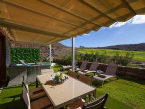un patio con mesa y sillas bajo una sombrilla grande en Vista Golf 20 by VillaGranCanaria, en Maspalomas