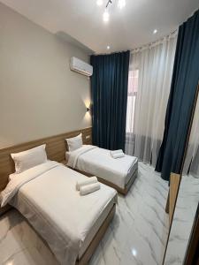 2 łóżka w pokoju hotelowym z niebieskimi zasłonami w obiekcie Sofiya Tashkent Hotel w Taszkiencie