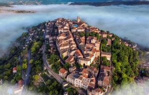 a town on top of a hill in the clouds at Rue du Barri in Cordes-sur-Ciel