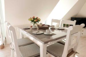 a white dining room table and chairs with flowers on it at Baabe Ferienwohnung 21 Kajuete Ref in Baabe