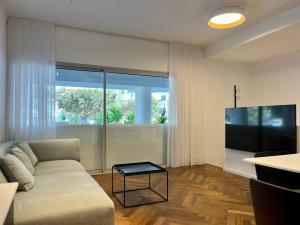 uma sala de estar com um sofá e uma televisão de ecrã plano em New apt - 3BD on the boulevard em Tel Aviv