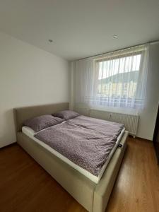 Ce lit se trouve dans un dortoir blanc doté d'une fenêtre. dans l'établissement Apartmán Majka, à Snina