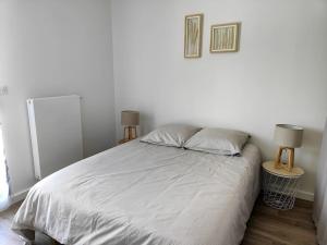 アンデルノ・レ・バンにあるLocation de vacances à Andernos - appartement 2 chambres dans résidence neuveの白いベッドルーム(ランプ2つ付きの大型ベッド1台付)