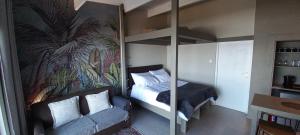 een slaapkamer met een stapelbed en een bank bij Mitford Marula in Morganʼs Bay