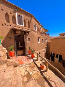 a building with potted plants in front of it at Kasbah El Hajja in Aït Ben Haddou