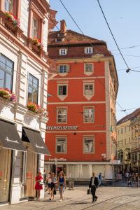Ein rotes Gebäude mit Leuten, die in einer Straße spazieren in der Unterkunft Kaiser Apartments - City Centre of Graz in Graz