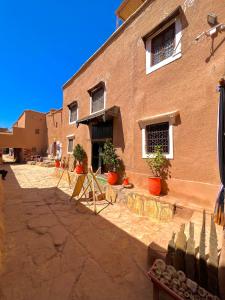 a brick building with potted plants in front of it at Kasbah El Hajja in Aït Benhaddou