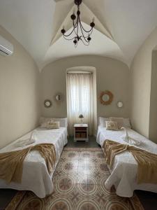 two beds in a room with a chandelier at Casa rural 3R in Don Álvaro