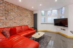 sala de estar con sofá de cuero rojo y TV en The Haven At The Lawrence Apartments en York