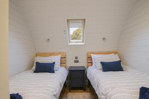 two beds in a small room with a window at Cedar in Bridport