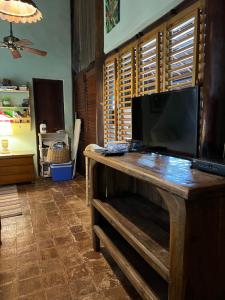 a living room with a television on a wooden table at Charmoso bangalô balinês pé na areia Outeiro das Brisas in Praia do Espelho