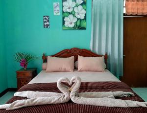 a bed with two heart shaped towels on it at New Taman Sari Homestay in Pawenang