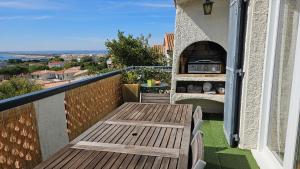 einen Balkon mit einem Holztisch und einem Pizzaofen in der Unterkunft Villa Farniente in Sète