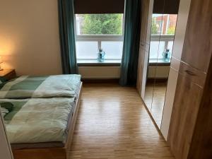 ein Schlafzimmer mit einem Bett und zwei Fenstern in der Unterkunft Ferienwohnung Stadtgracht in Nordhorn