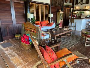 a living room with a couch and a table at Charmoso bangalô balinês pé na areia Outeiro das Brisas in Praia do Espelho