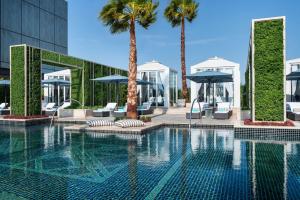 科威特Waldorf Astoria Kuwait的一座棕榈树和遮阳伞的游泳池