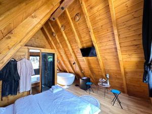 a bedroom with a bed and a tub in a wooden ceiling at Thethi Villas in Theth