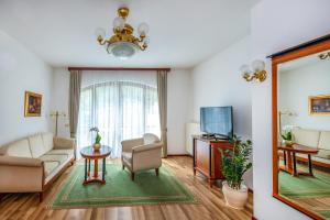 ein Wohnzimmer mit einem Sofa und einem TV in der Unterkunft Szarvaskút Hotel in Zirc
