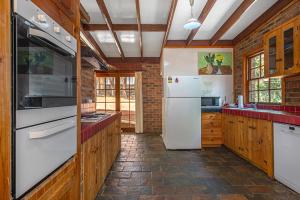 a kitchen with a white refrigerator and wooden cabinets at Juliana's Cottage 4 Bedroom Katoomba Home in Katoomba