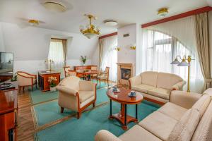 a living room with a couch and chairs and a table at Szarvaskút Hotel in Zirc