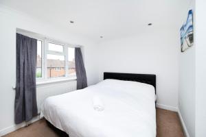 a bedroom with a white bed and a window at 3BR Home A Cosy Ealing Haven in London in Northolt