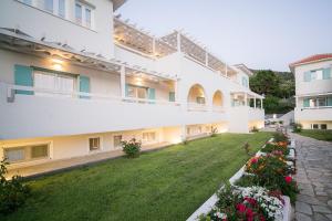 un gran edificio blanco con flores en un patio en Sunrise Village Hotel Apartments, en Skopelos Town