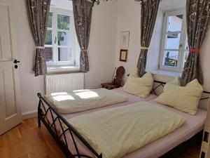 2 Betten in einem Zimmer mit 2 Fenstern in der Unterkunft Ferienwohnungen im Lüftlmalereck, Mussldomahaus in Oberammergau