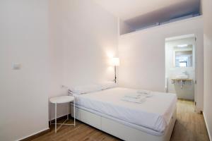 Dormitorio blanco con cama blanca y taburete en VLC Host - Gulliver Riverside en Valencia