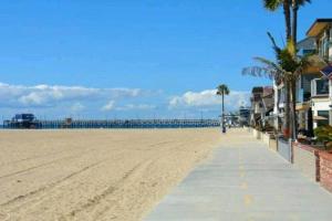 a sandy beach with a pier in the background at Newport Beach Living (1 blk to beach and 25 min to Disney) in Newport Beach