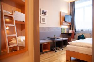 a bedroom with a bunk bed and a desk with a computer at JUFA Hotel Kaprun in Kaprun