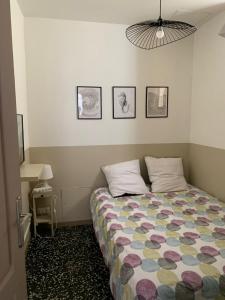 Dormitorio pequeño con cama y edredón colorido en Appartement au coeur du quartier de la Roquette, en Arles