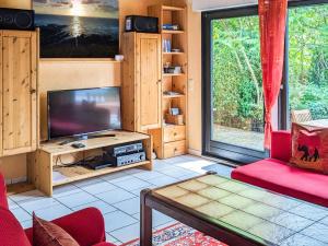 sala de estar con TV y sofá rojo en Im Herzen der Natur, en Herdwangen-Schönach