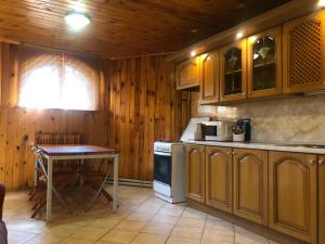 cocina con armarios de madera, mesa y fogones en Apartment complex, en Sumy