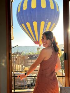 a woman standing on a balcony with a hot air balloon at Aysel Inn House in Avcılar