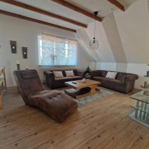 a living room with leather furniture and a table at Ferienwohnung Lerchi's Ankerplatz in Barßel