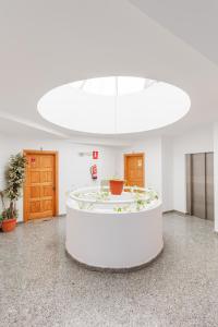 une grande chambre blanche avec une table au milieu dans l'établissement EL VELERO, à Corralejo