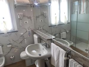 ein Badezimmer mit einem Waschbecken, einem WC und einem Spiegel in der Unterkunft Hotel Malpensafiera in Bernate Ticino