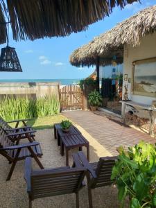 a patio with benches and a table and a hut at Espaço Fateixa in Jericoacoara