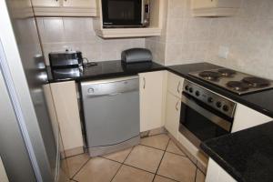 a small kitchen with a stove and a microwave at Strandloper 3 in Margate