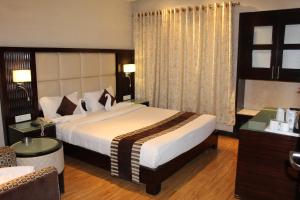 una habitación de hotel con una cama grande y una silla en Hotel La Abode, en Hāmīrgarh