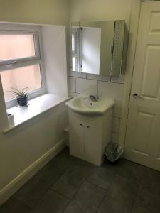 a white bathroom with a sink and a window at Central Morecambe, minimalist seaside flat N.1 in Morecambe