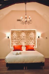 1 dormitorio con 1 cama con almohadas de color naranja y lámpara de araña en Le Moulin du Château de Horgues en Horgues