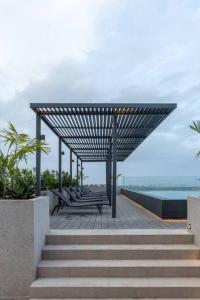 una fila di panchine sedute su una passerella accanto a una piscina di The Lennox Studio @Airport Residential a Accra