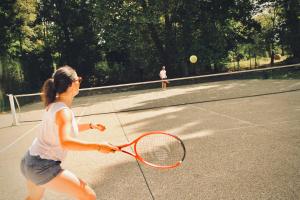 una donna che dondola una racchetta da tennis su un campo da tennis di Le Moulin du Château de Horgues a Horgues