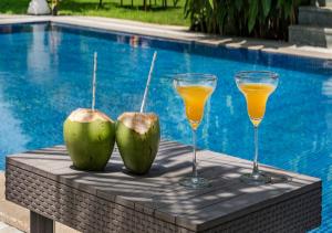- deux noix de coco et deux verres de jus à côté de la piscine dans l'établissement SaffronStays Osaree, Kihim - pet-friendly pool villa perfect for a workcation, à Alibaug
