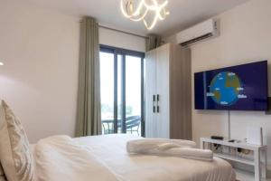 a white bedroom with a bed and a chandelier at The Lennox Studio @Airport Residential in Accra +96 photos