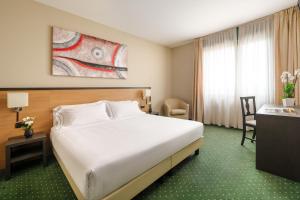 una camera d'albergo con un grande letto e una scrivania di Hotel King, by R Collection Hotels a Varedo