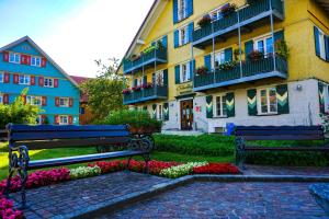 un banco de parque frente a un edificio con flores en Ferienwohnung BergPfote en Scheidegg