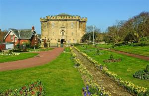 a castle in the middle of a park with flowers at Morpeth town centre - Cottingburn House in Morpeth